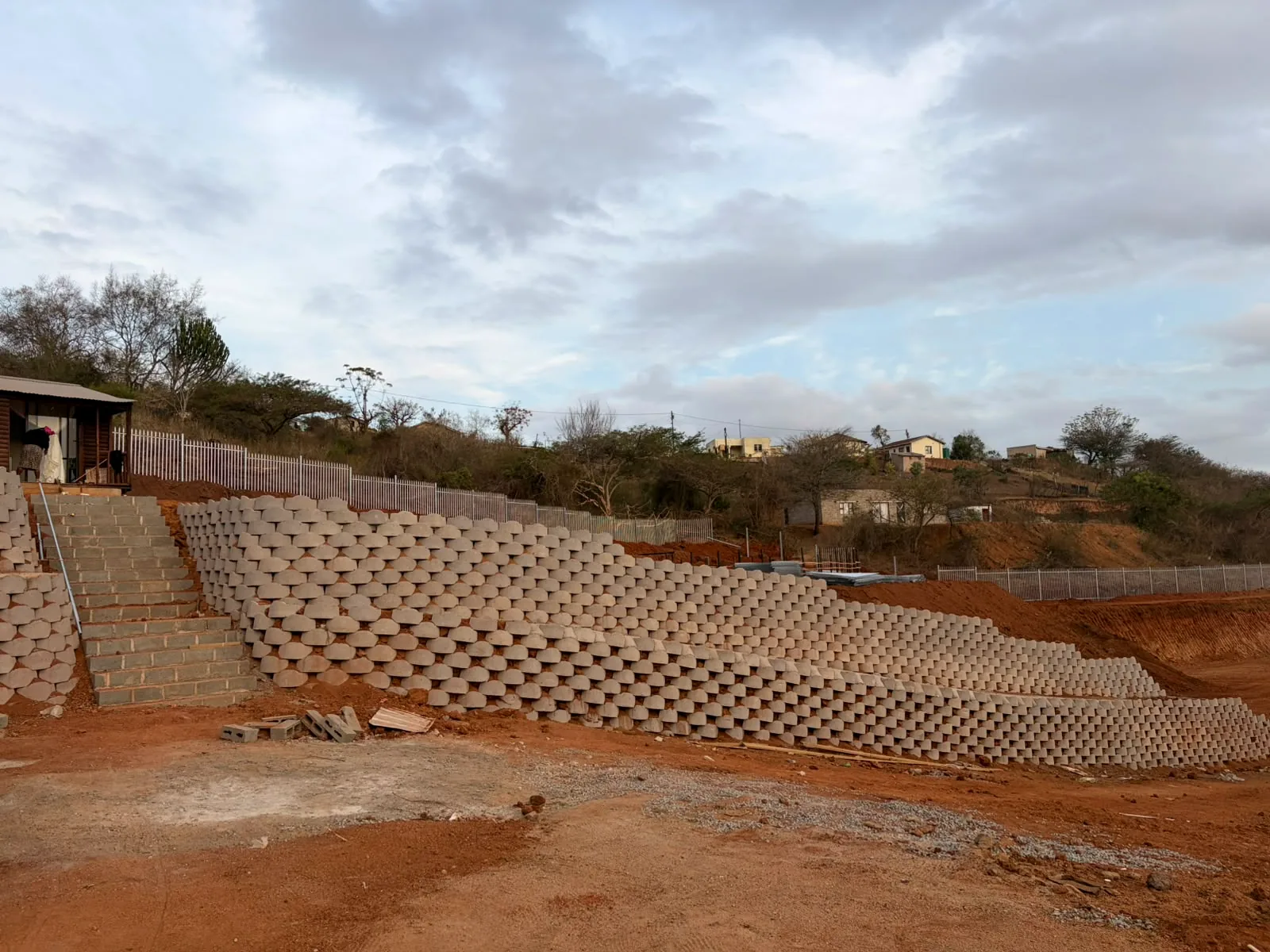 Completed retaining wall and access stairs on a sloped construction site